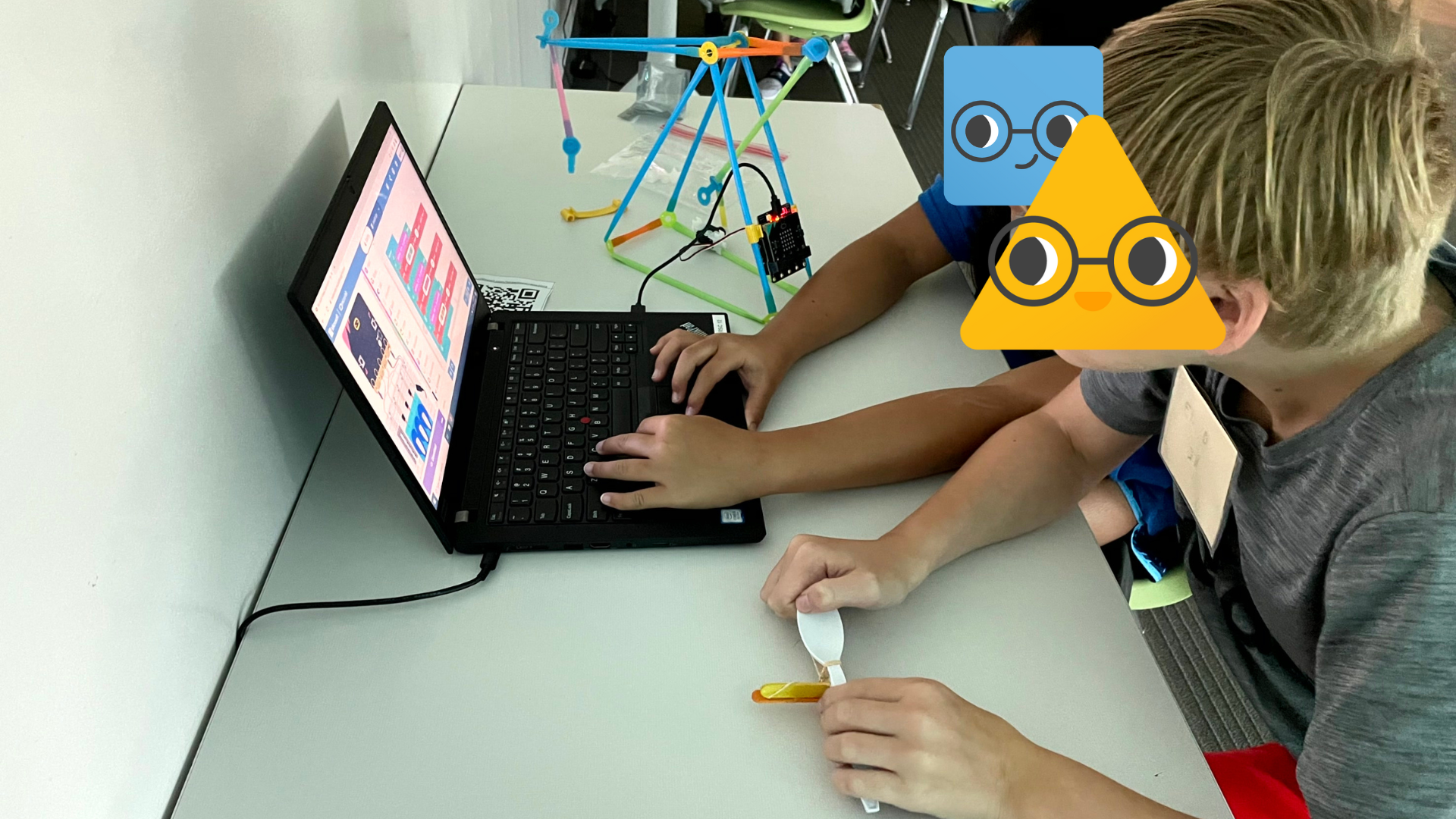 Two students working with a laptop and Strawbees.