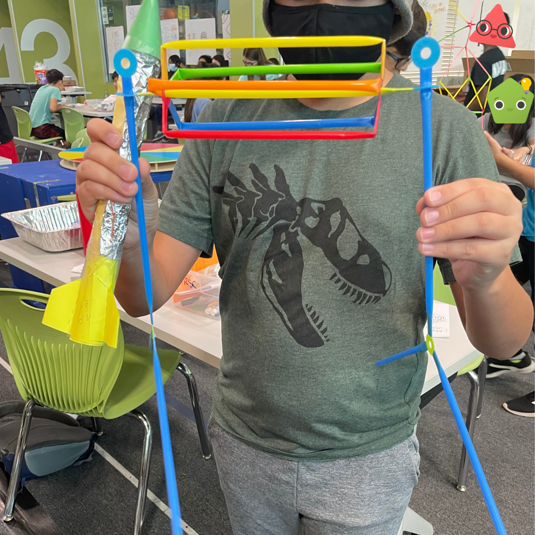A student holds up their own Strawbees invention.