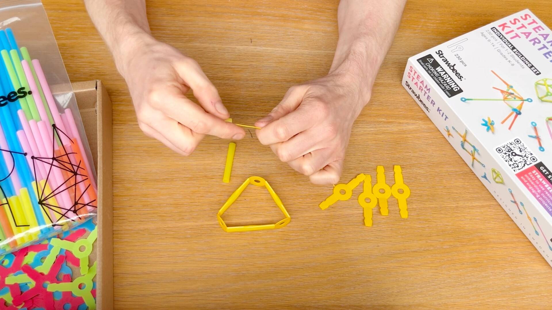 Hands building Strawbees sculpture.