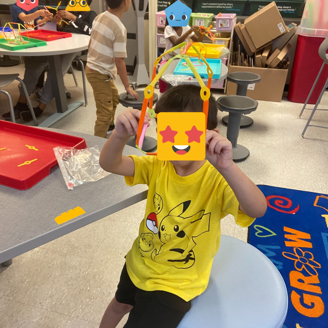 A student holding up a build with Strawbees.