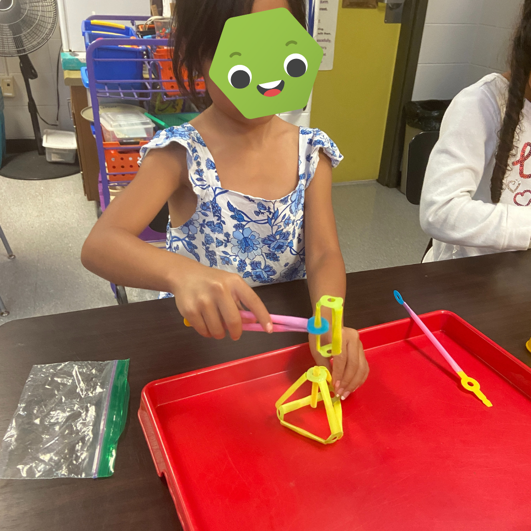 A student with a hammer made of Strawbees.