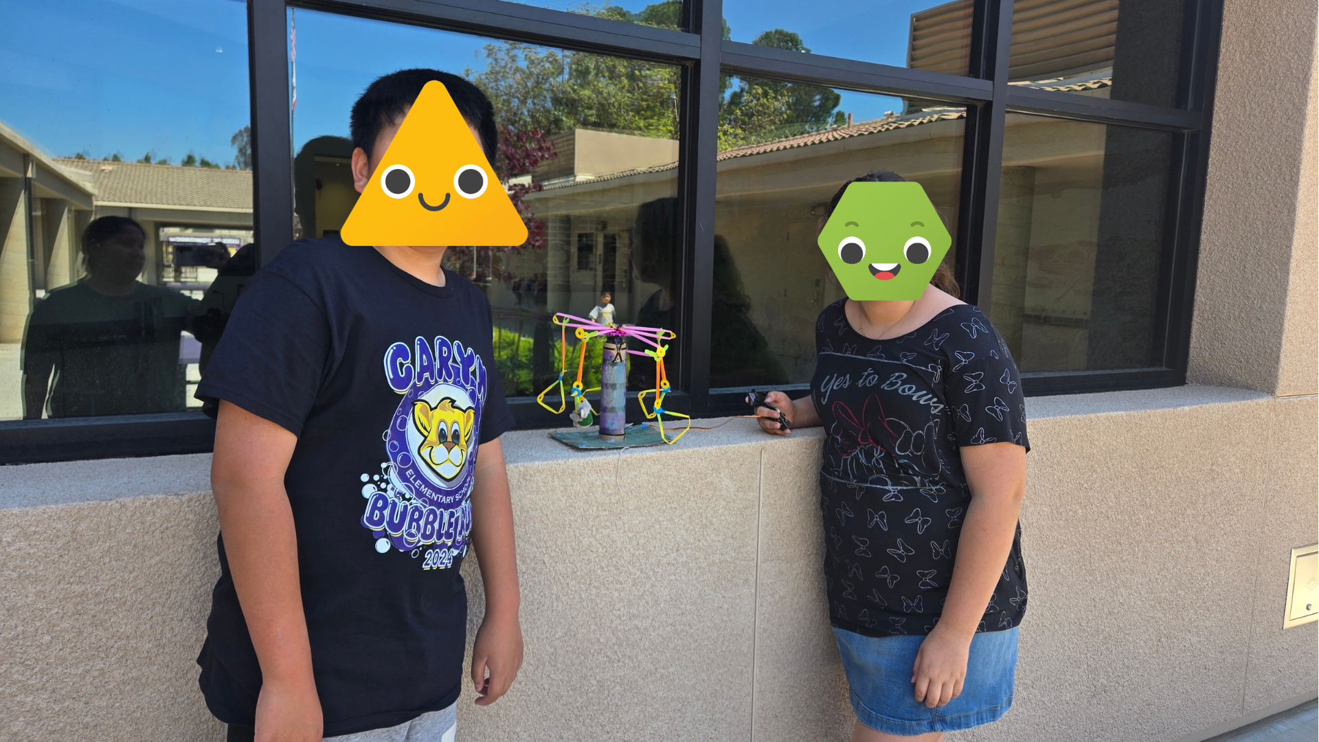 Two students standing next to a Strawbees build.