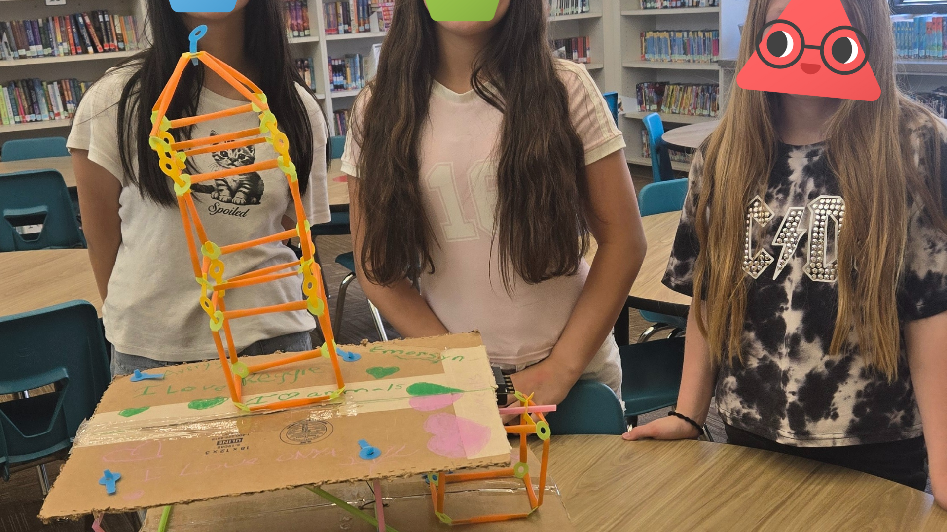Three students showing their earthquake build.