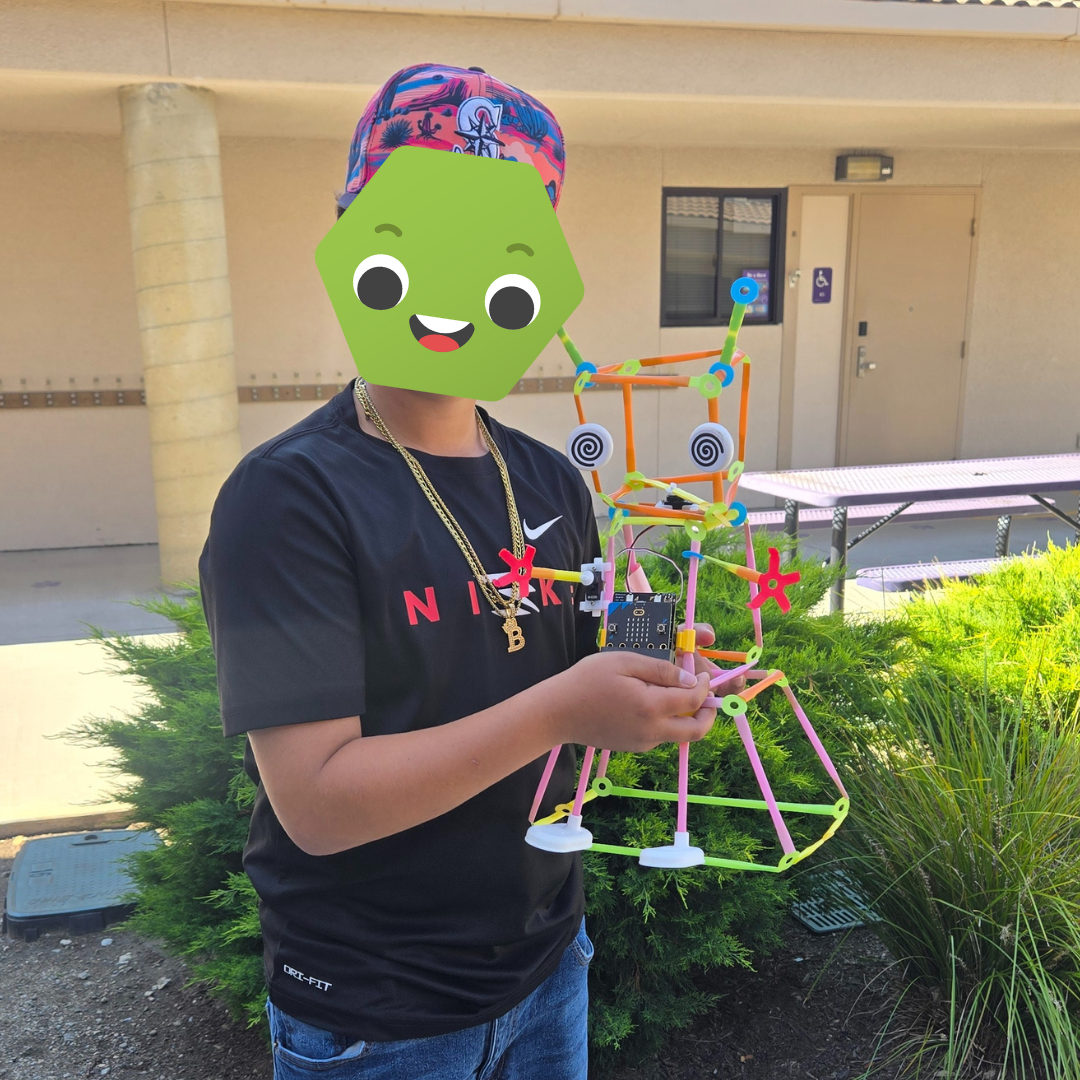 A student holding a build from Strawbees.